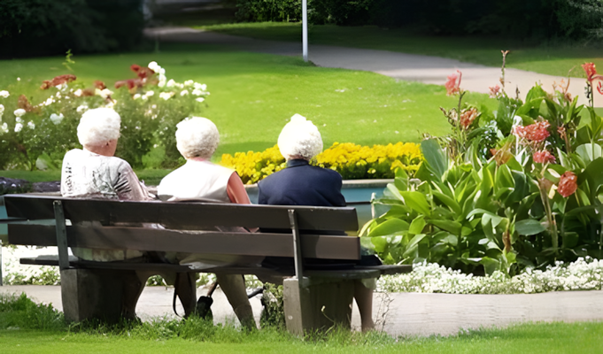 Drei ältere Damen sitzen in einem Park auf einer Bank