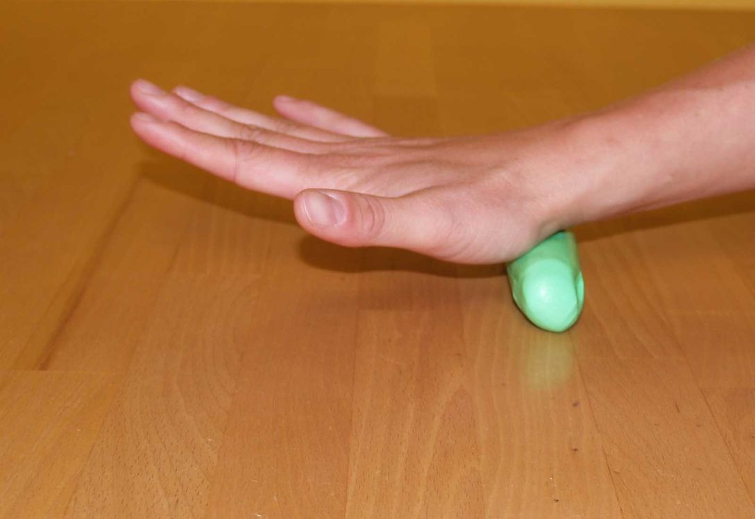 Eine Hand knetet etwas grüne Masse