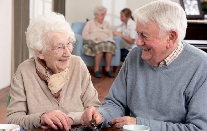 Eine alte Frau und ein alter Mann sitzen lachend an einem Tisch
