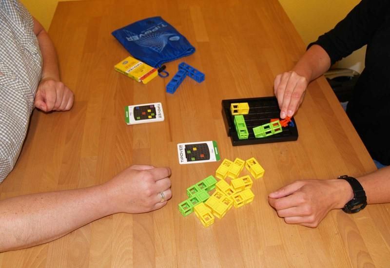 Zwei Personen bauen mit Bauklötzen an einem Tisch