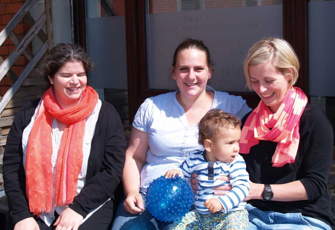 Das Team von Ergo Vital mit einem Kind auf dem Schoß